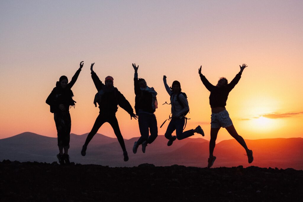 Friends jumping together during a sunset group trip